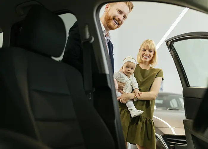 woman looking into new car holding toddler